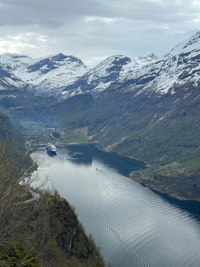 A cruise ship at anchor in Norway's Geirangerfjord, ringed by snow-capped peaks