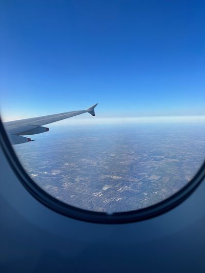 The view from a window seat — an airplane wing over patchwork land far below
