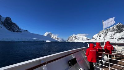 Passengers on an expedition ship deck taking in Antarctica’s snow-capped mountains